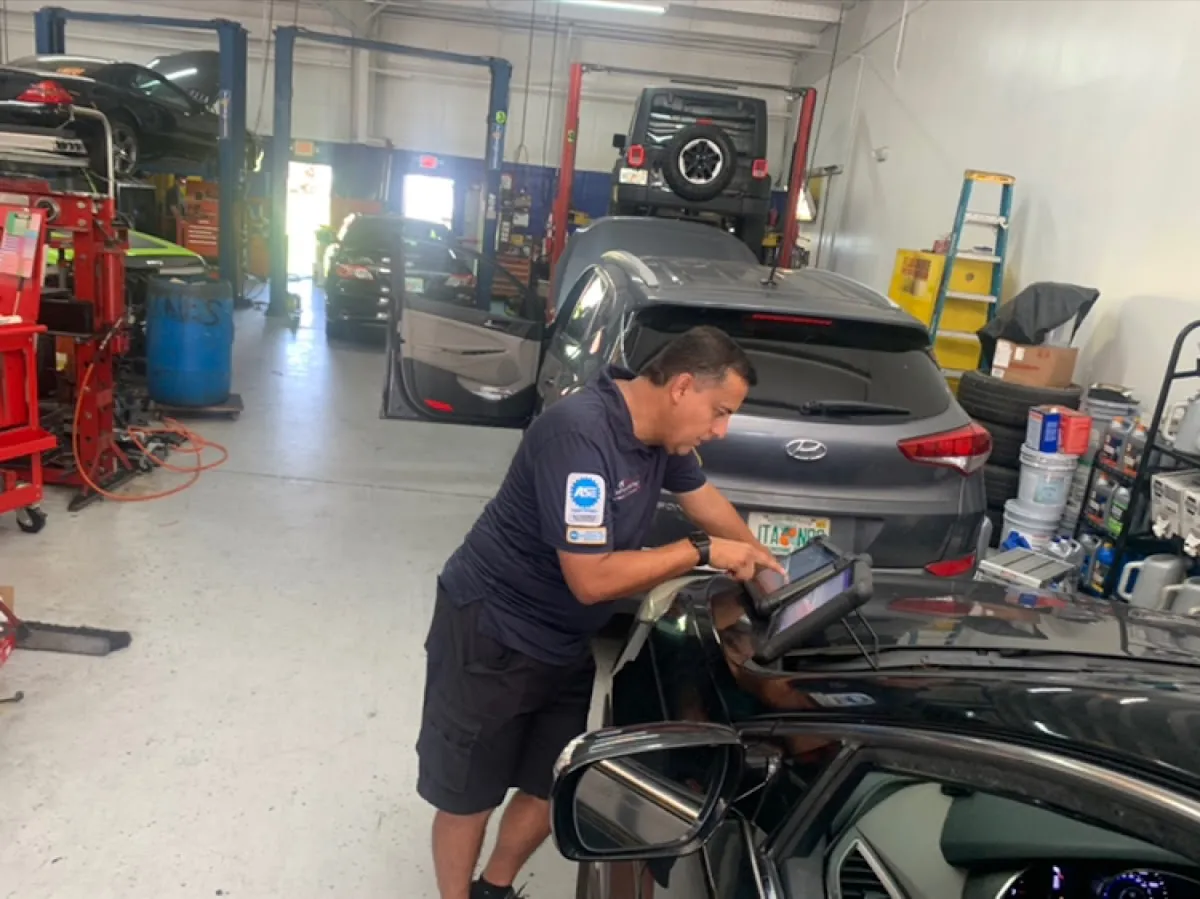 ASE certified technician using diagnostic tablet at RepairTech Automotive in Kissimmee FL