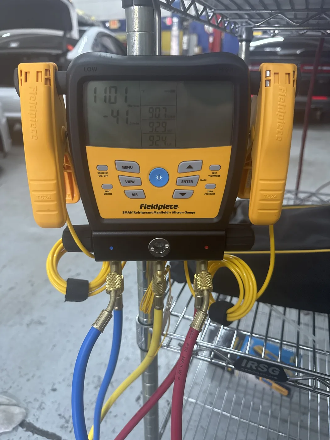 Fieldpiece SMAN refrigerant manifold and micron gauge connected to a vehicle A/C system at RepairTech Automotive in Kissimmee, reading 1101 microns during a vacuum decay test